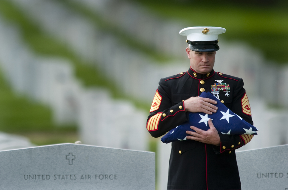 A Marine honor guard holds the flag that covered the casket of a soldier during funeral services at Arlington National Cemetery.