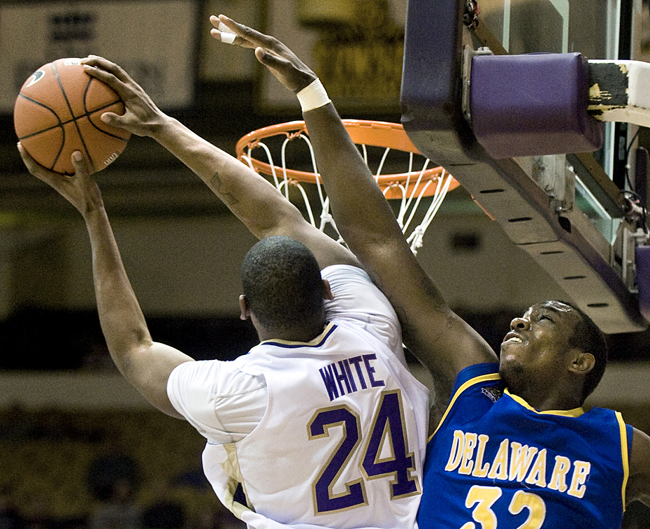 James Madison's Darren White dunks the ball over Delaware's Josh Brinkley during first-half action against Delaware at the JMU Convo on Monday night.
