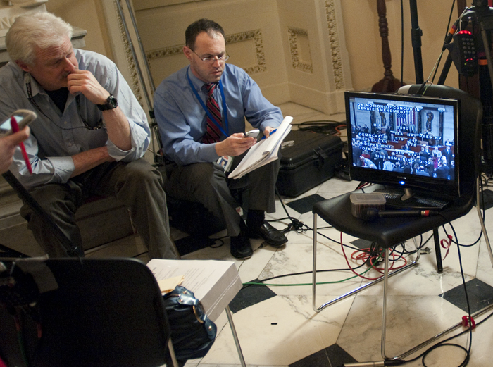 A television crew watches the historic vote on a monitor outside of the House Chambers.